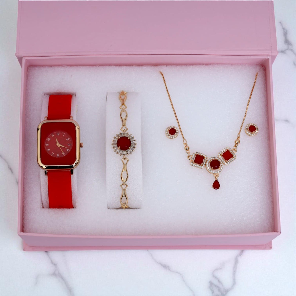 Elegant red women's gift set including watch, bracelet, necklace and earrings in pink box on marble surface