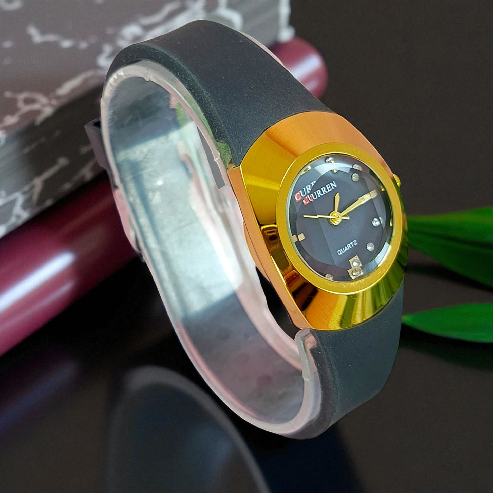 Gold & black ladies watch angled view with gold case, black strap and crystal markers