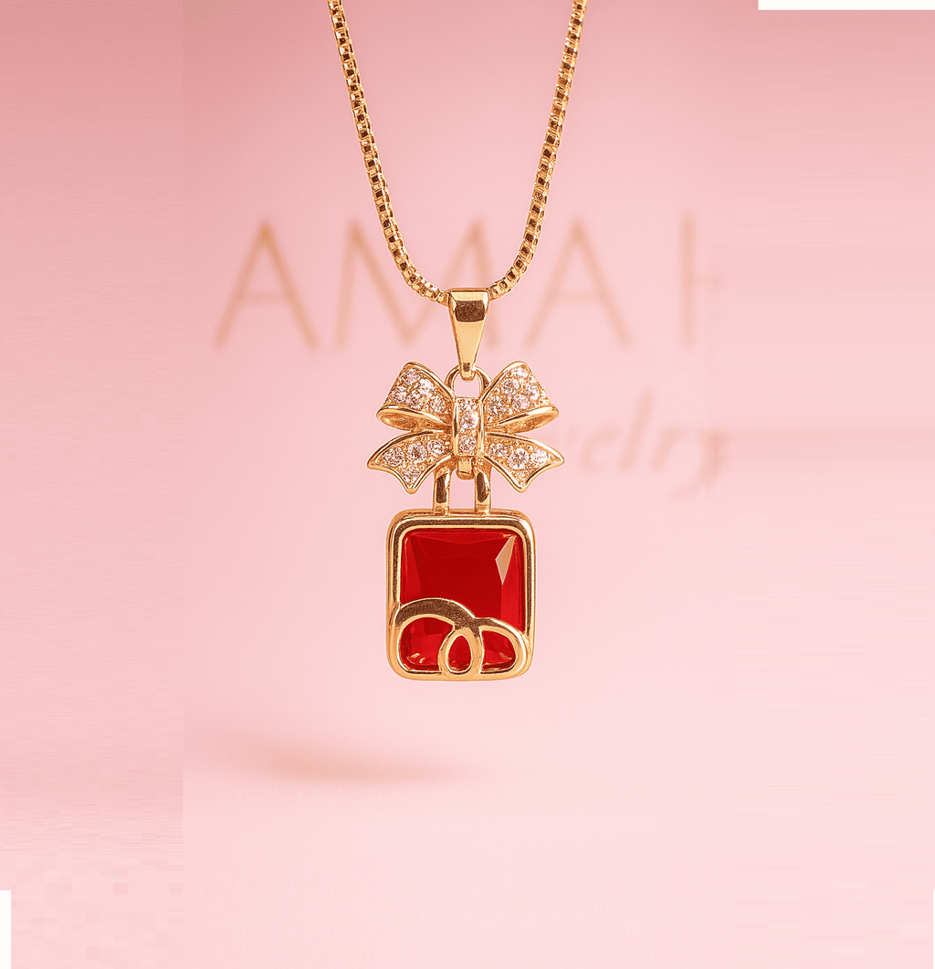 Gold necklace with red square pendant and bow design on pink background