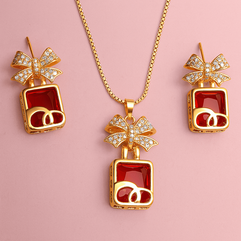Gold bow pendant necklace and earrings set with red stones arranged on pink background